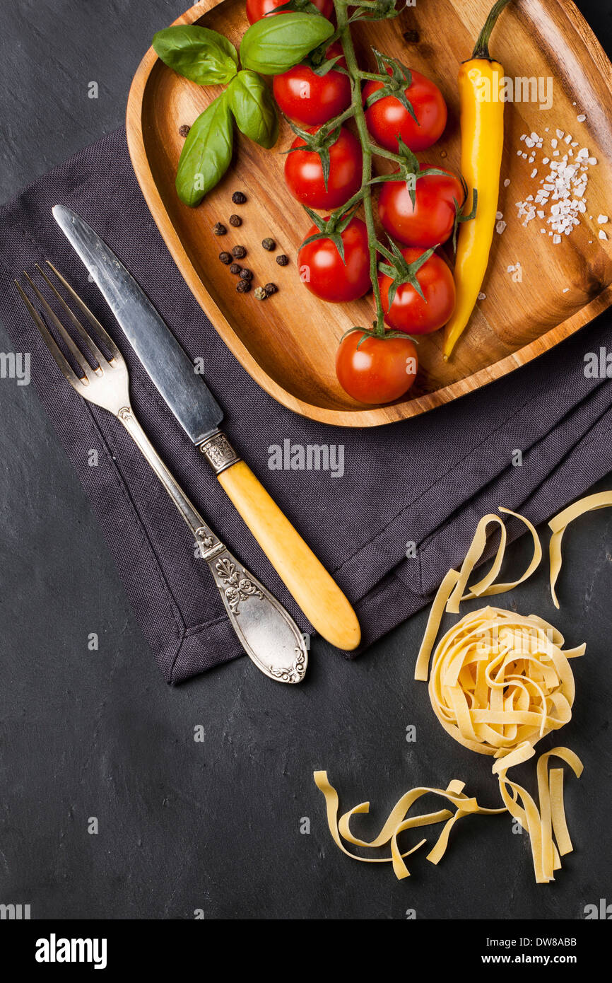 Tomatoes on the vine, basil and yellow chili served on wooden dish Stock Photo