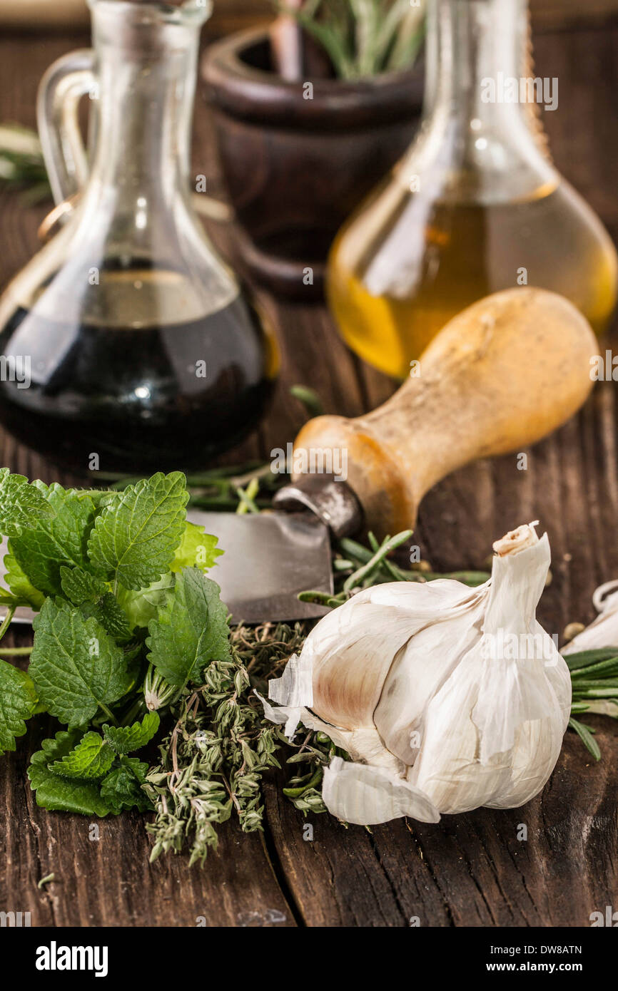 vintage knife with garlic, mint and thyme, oil and vinegar in vintage bottles on old wooden table Stock Photo