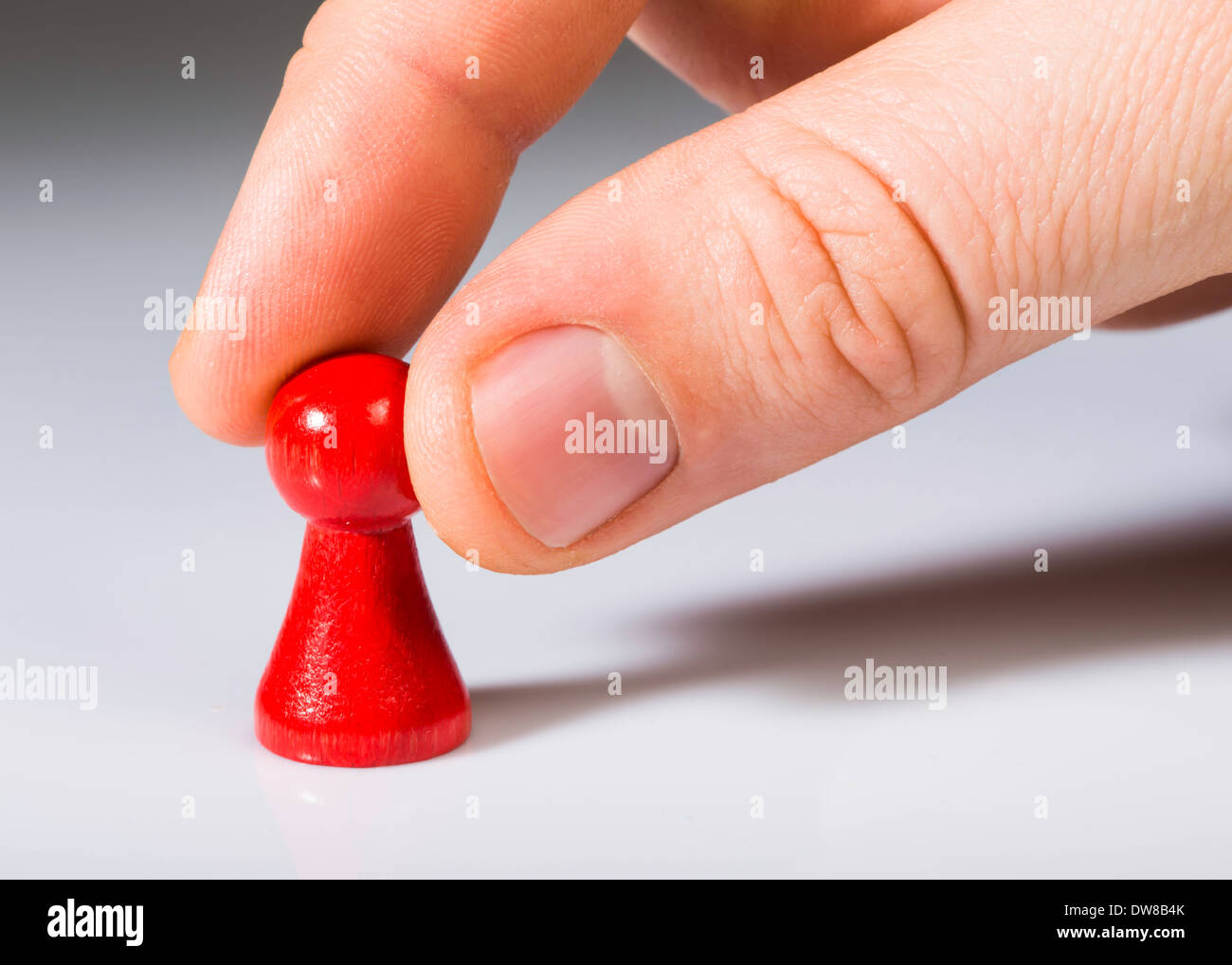 Hand holding red pawn on white background. Close up Stock Photo