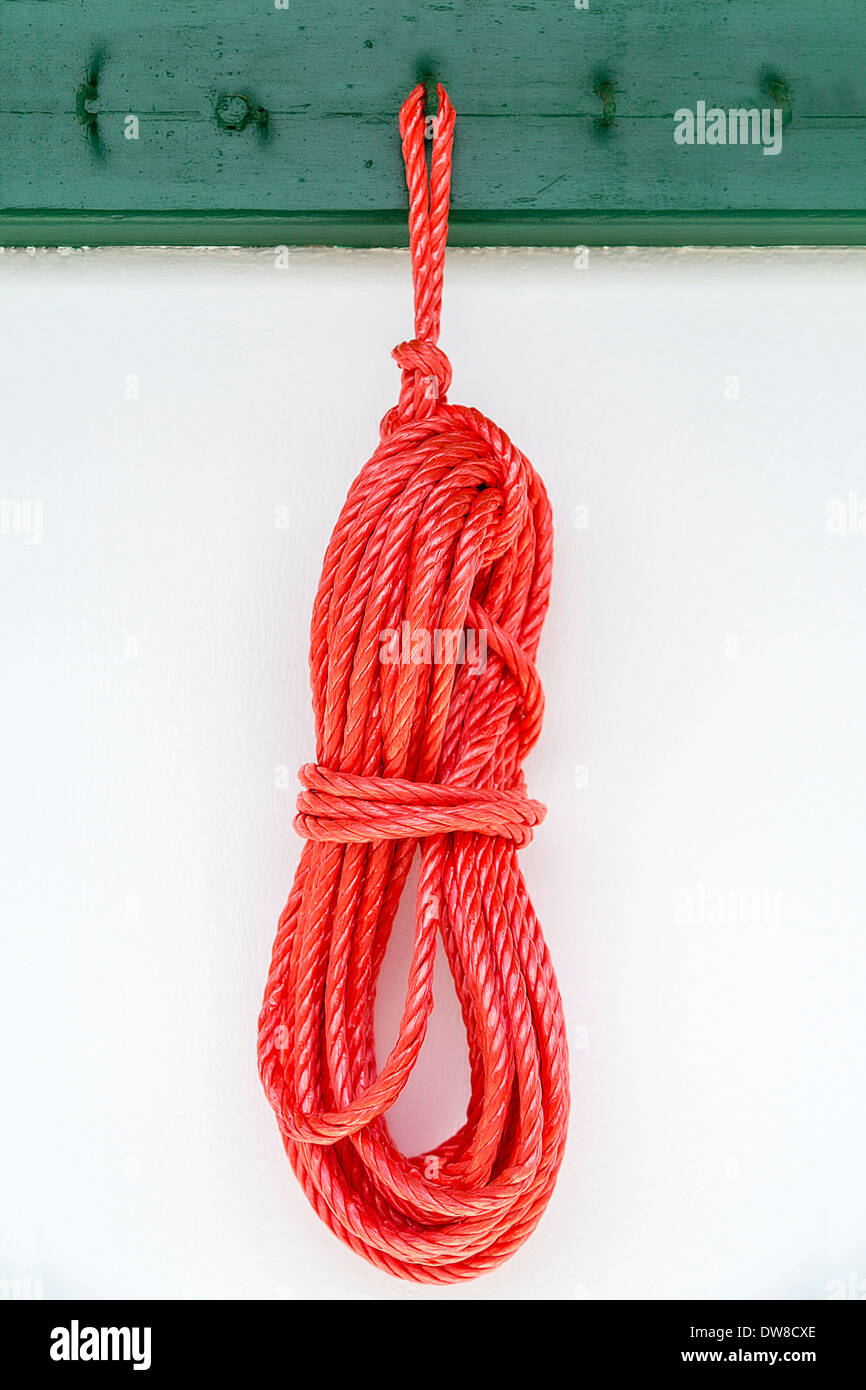 red rope hanging on a green hook on a white wall Stock Photo - Alamy