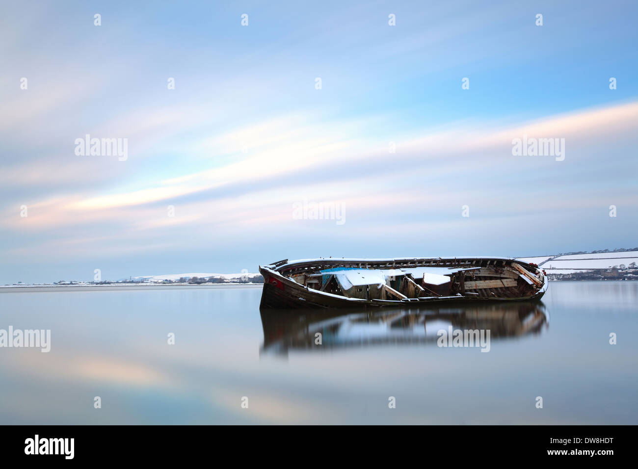 Snow covered wreck of old barge in tidal river at sunset Fremington Quay River Taw near Barnstaple North Devon England December Stock Photo