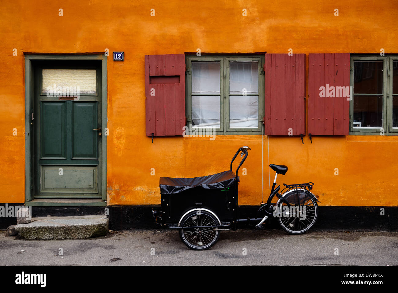 Photograph of a traditional danish bicycle standing in front of an orange house in Copenhagen. Stock Photo