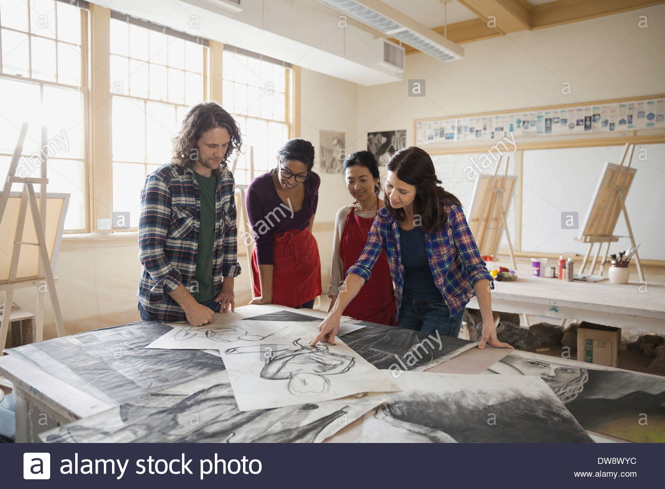 Students analyzing charcoal drawings in art class Stock Photo