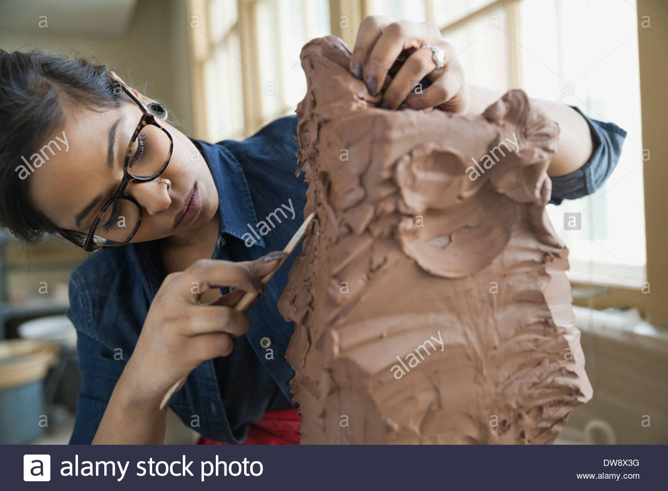 Artist working on clay sculpture in art studio Stock Photo