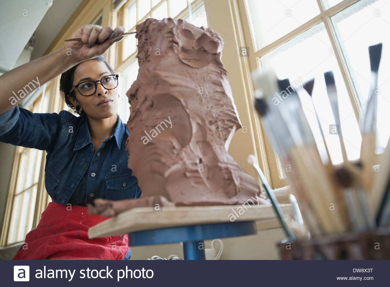 Artist working on clay sculpture in art studio Stock Photo
