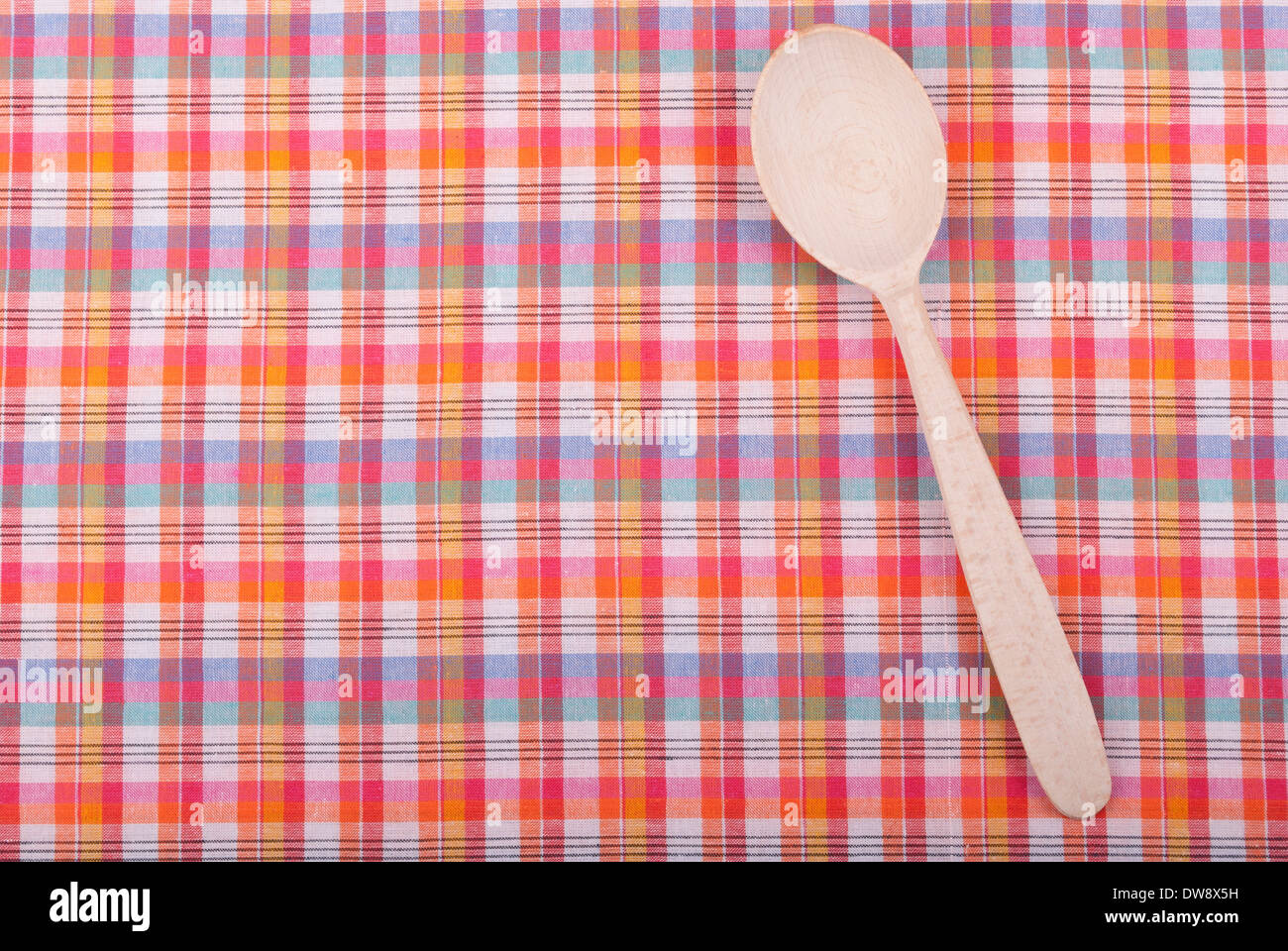 Wooden spoon on checkered tablecloth. Stock Photo