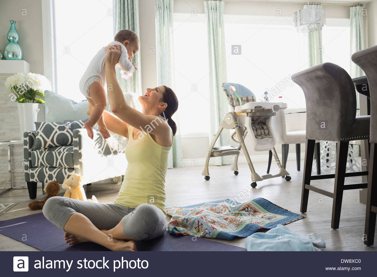 Fit mother lifting baby on exercise mat at home Stock Photo