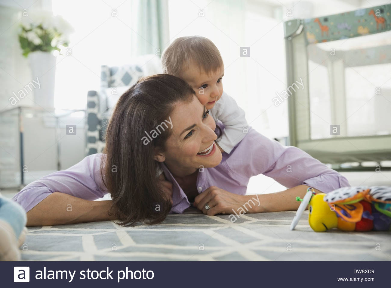 Cheerful woman playing with baby girl at home Stock Photo