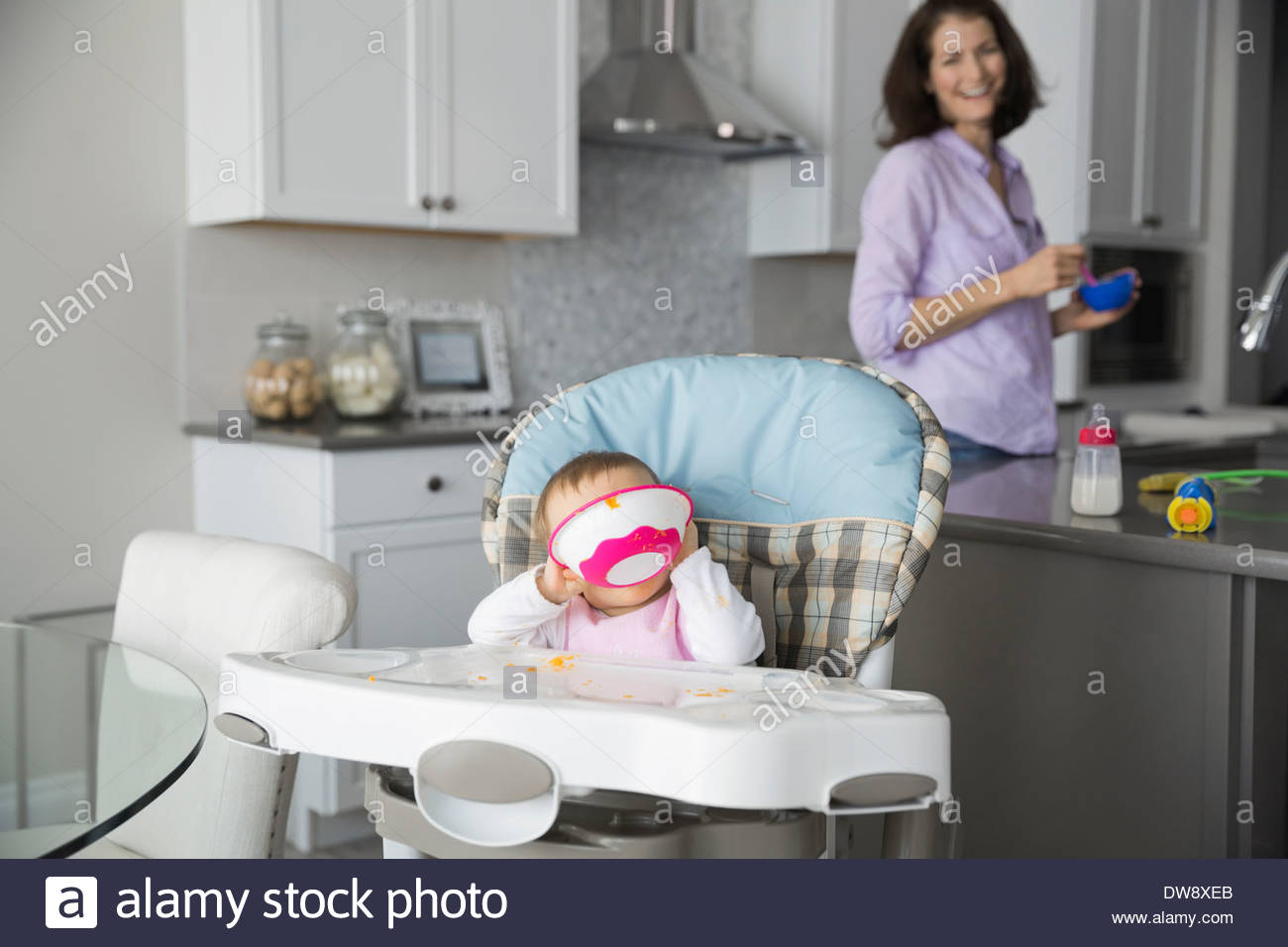 Baby sitting in high chair at home eating Stock Photo