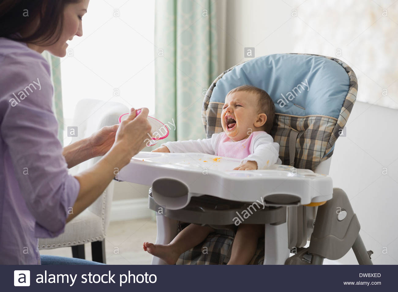 Mother feeding crying baby at home Stock Photo