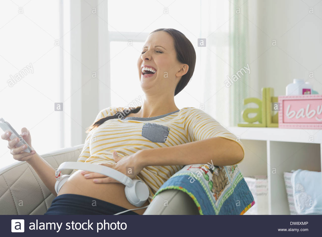 Pregnant woman with headphones on her belly Stock Photo