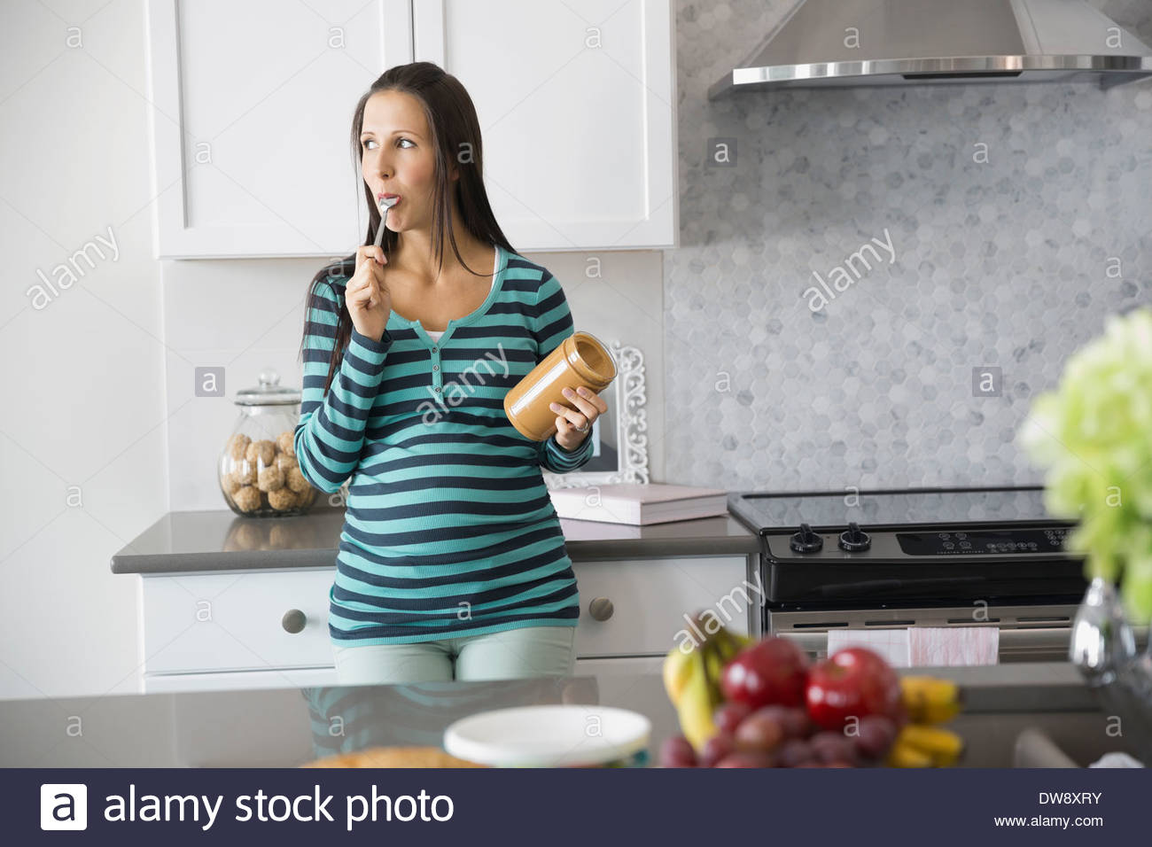 Pregnant woman eating peanut butter in kitchen Stock Photo Alamy