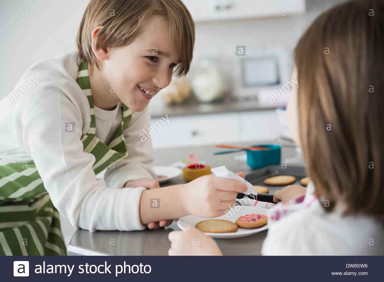 Siblings decorating cookies in kitchen Stock Photo