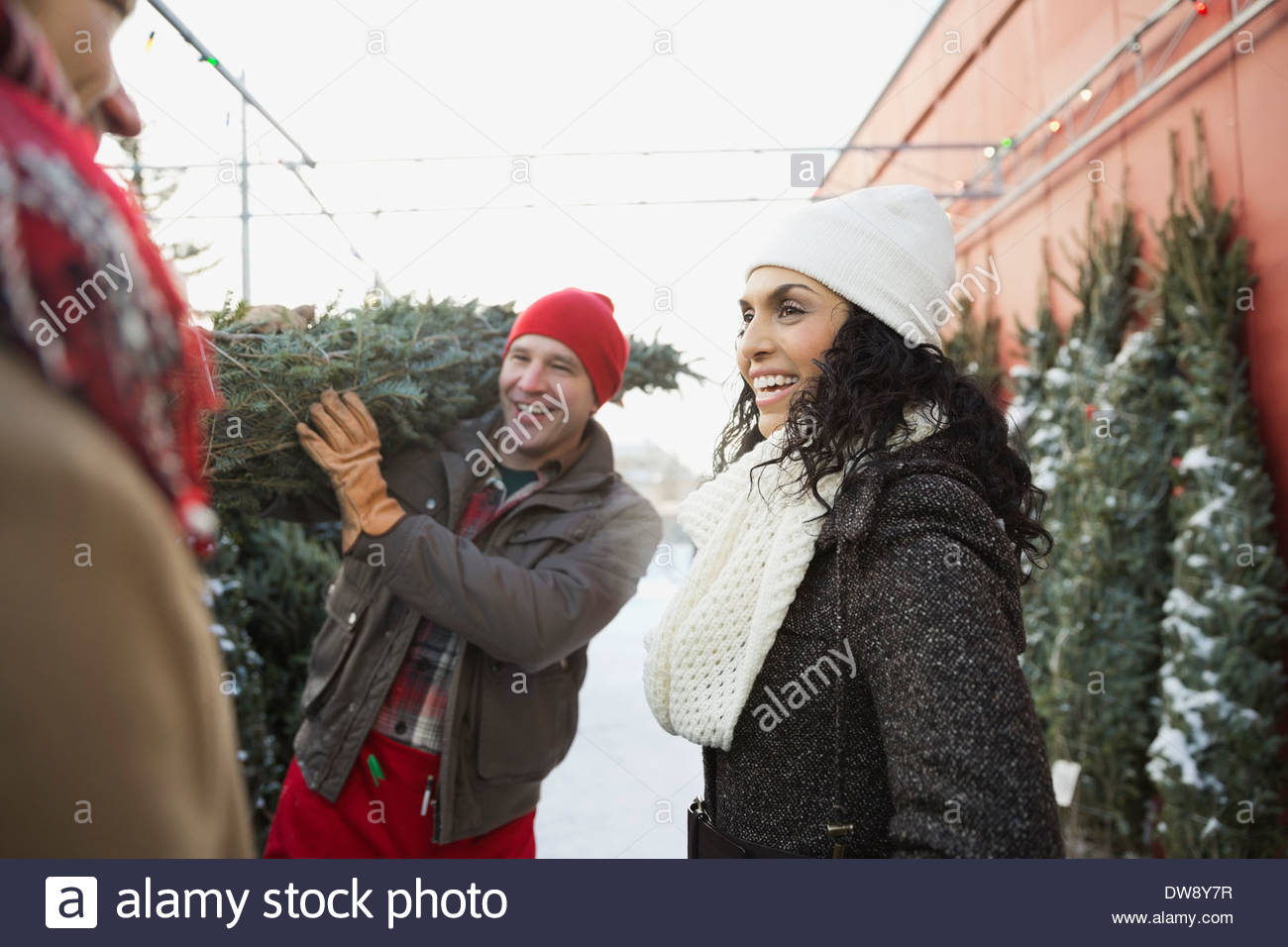 Woman with tree lot owner carrying Christmas tree Stock Photo