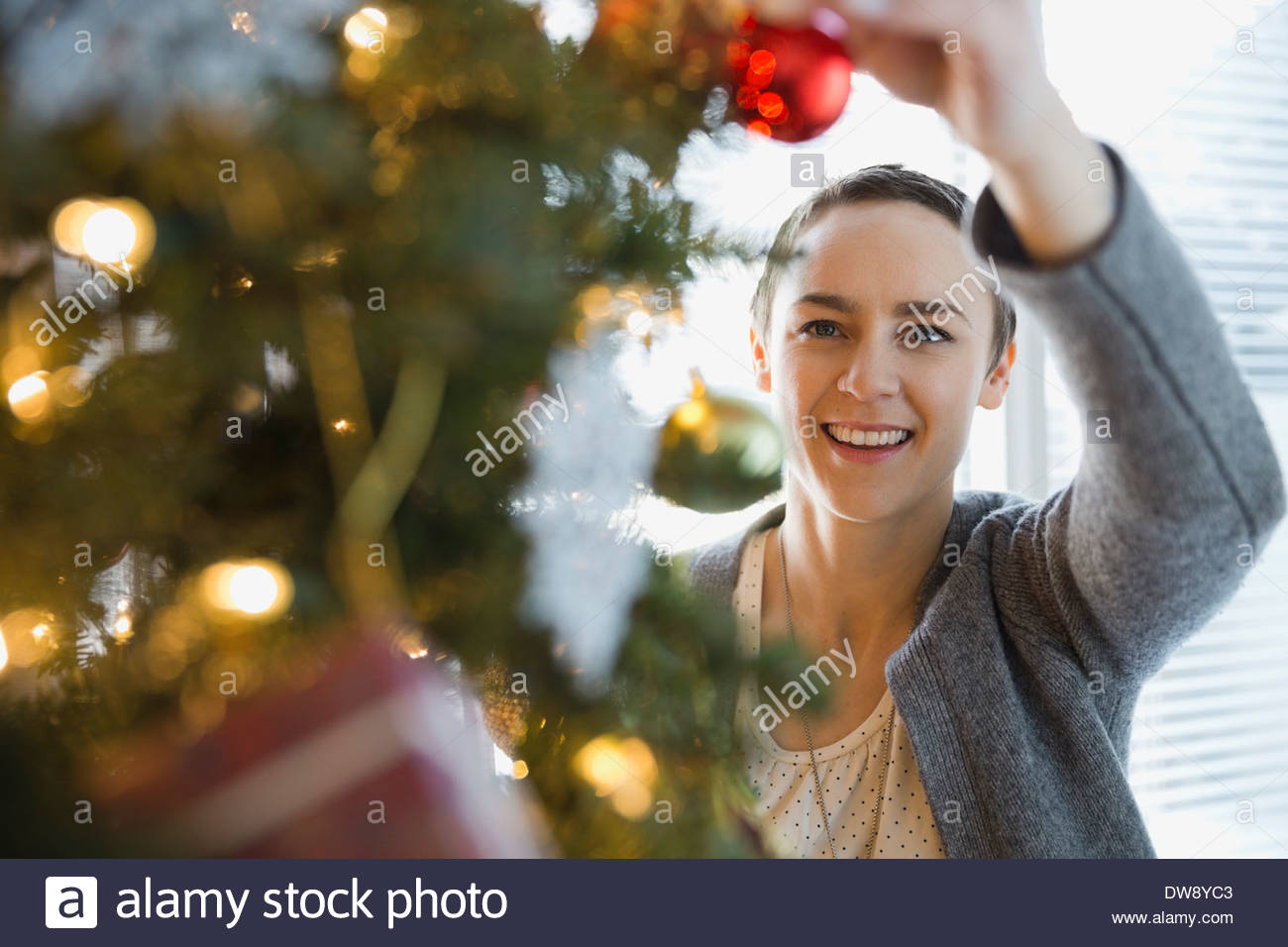 Woman decorating Christmas tree at home Stock Photo