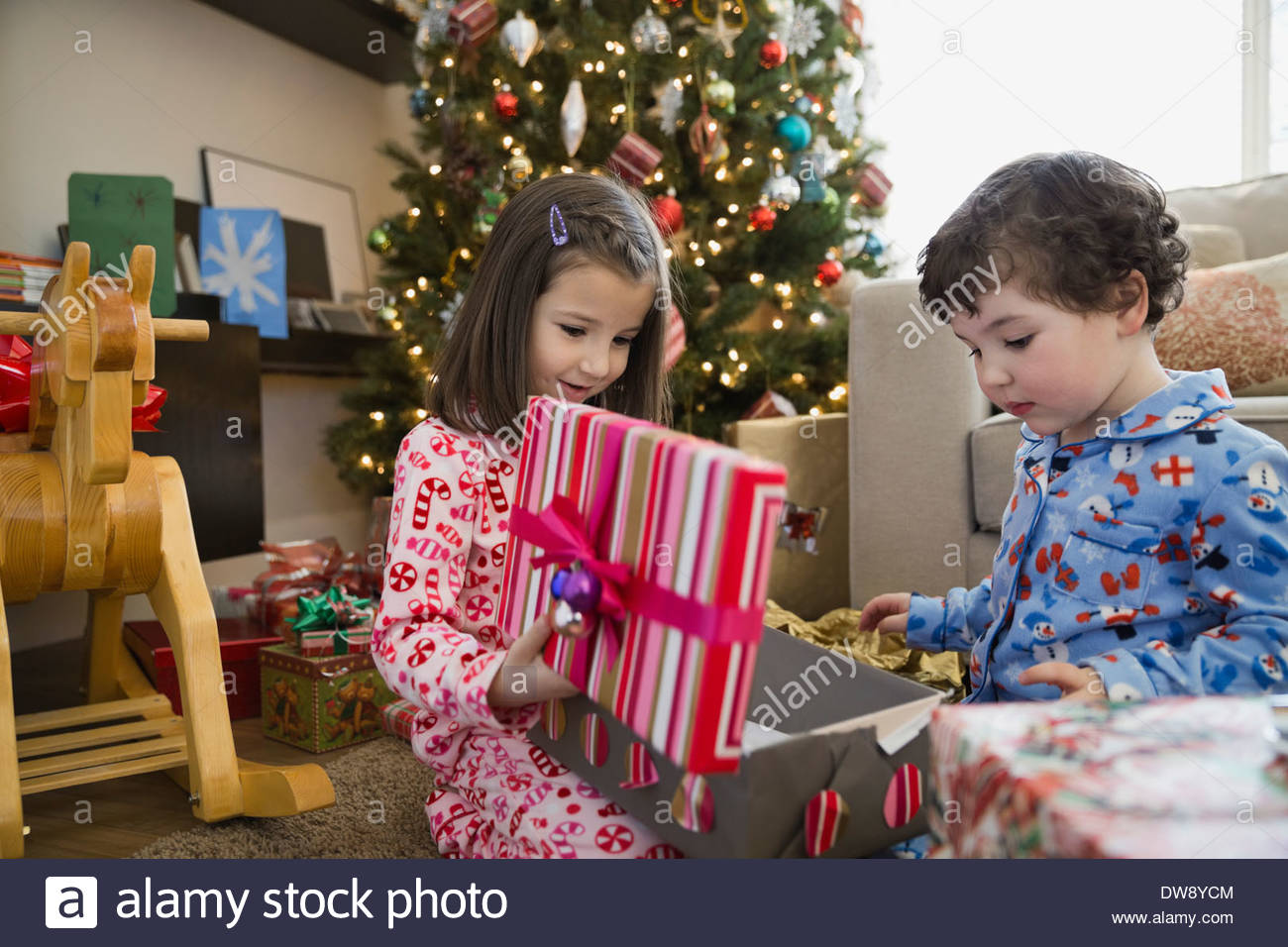 Siblings opening Christmas gift at home Stock Photo