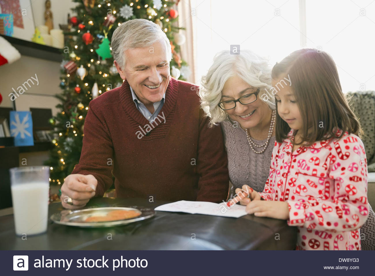 Grandparents helping girl write letter to Santa Claus Stock Photo
