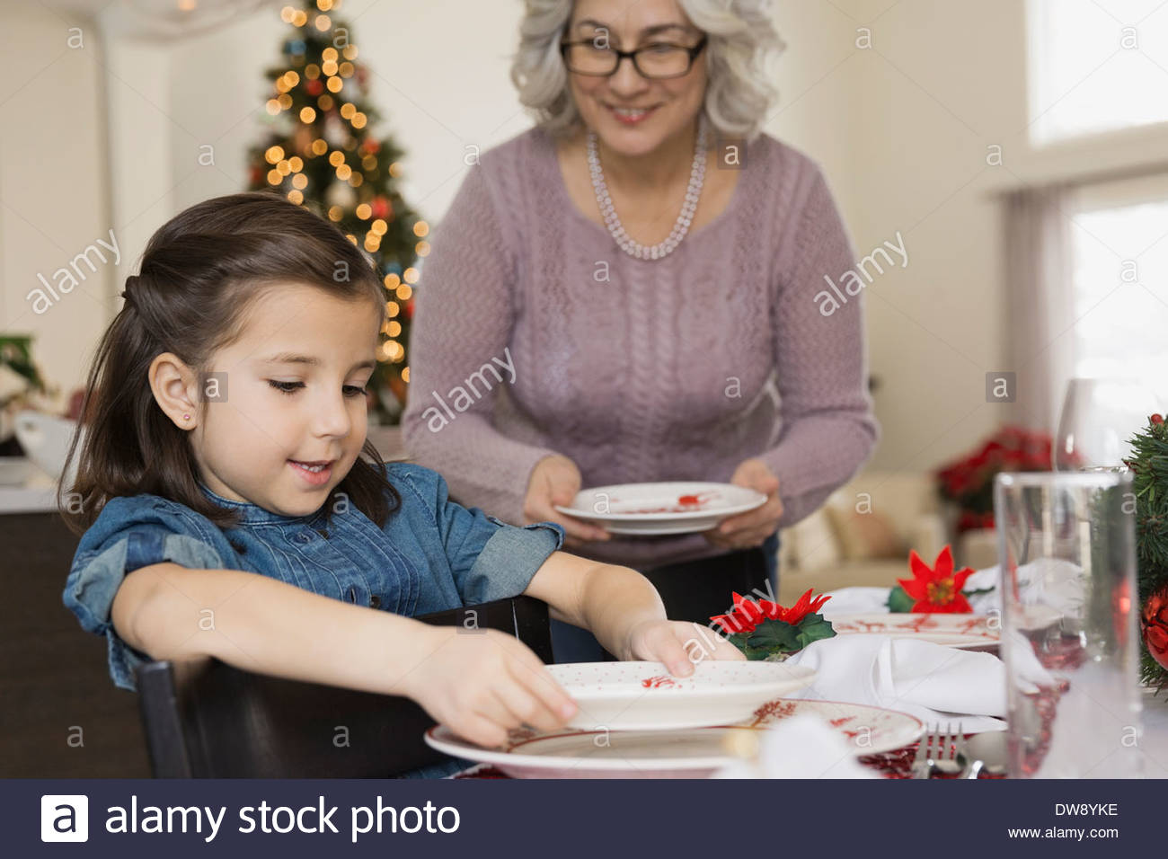 Grandmother and granddaughter setting table at Christmas Stock Photo