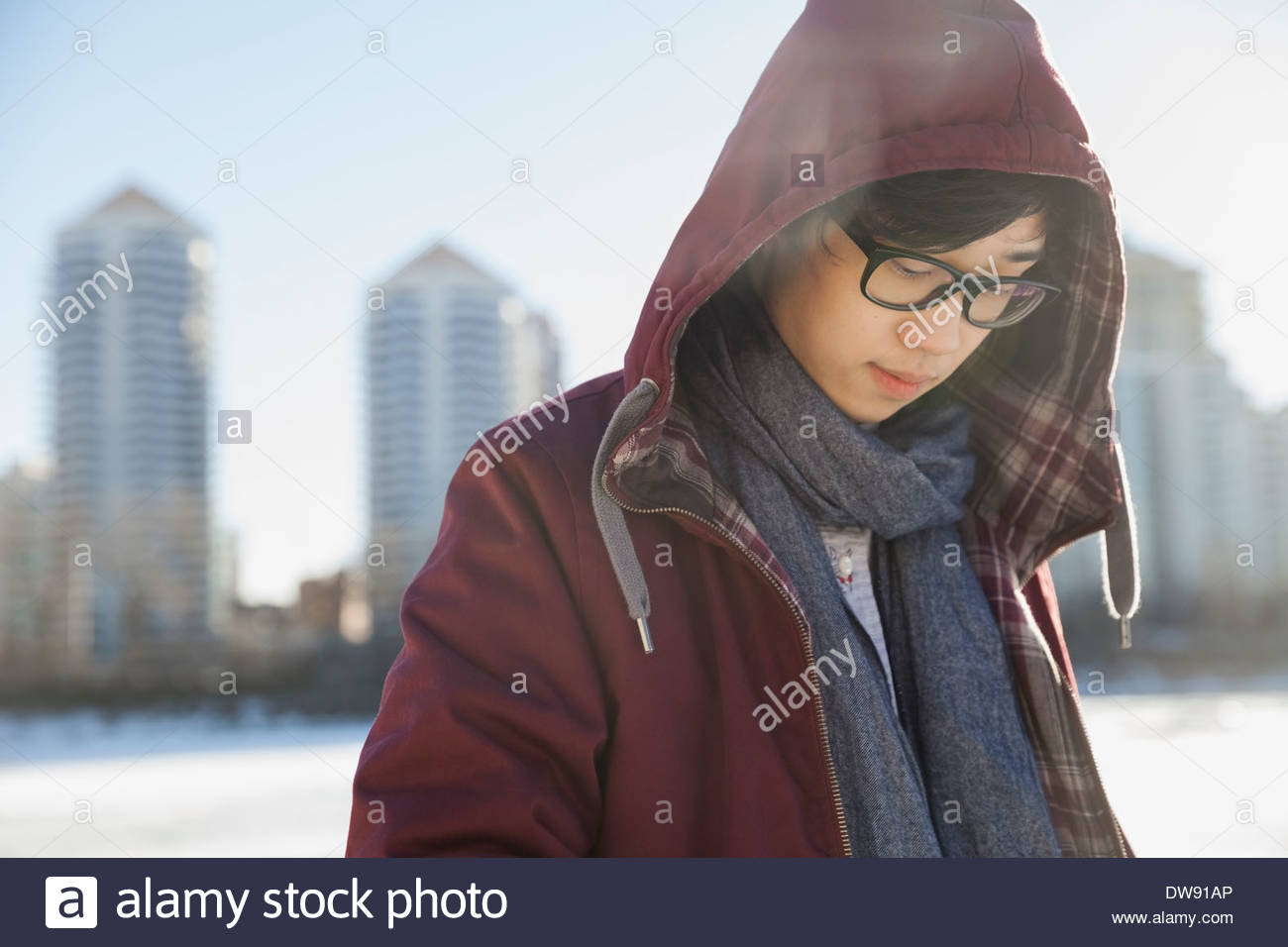 Young man with hooded jacket looking down outdoors Stock Photo