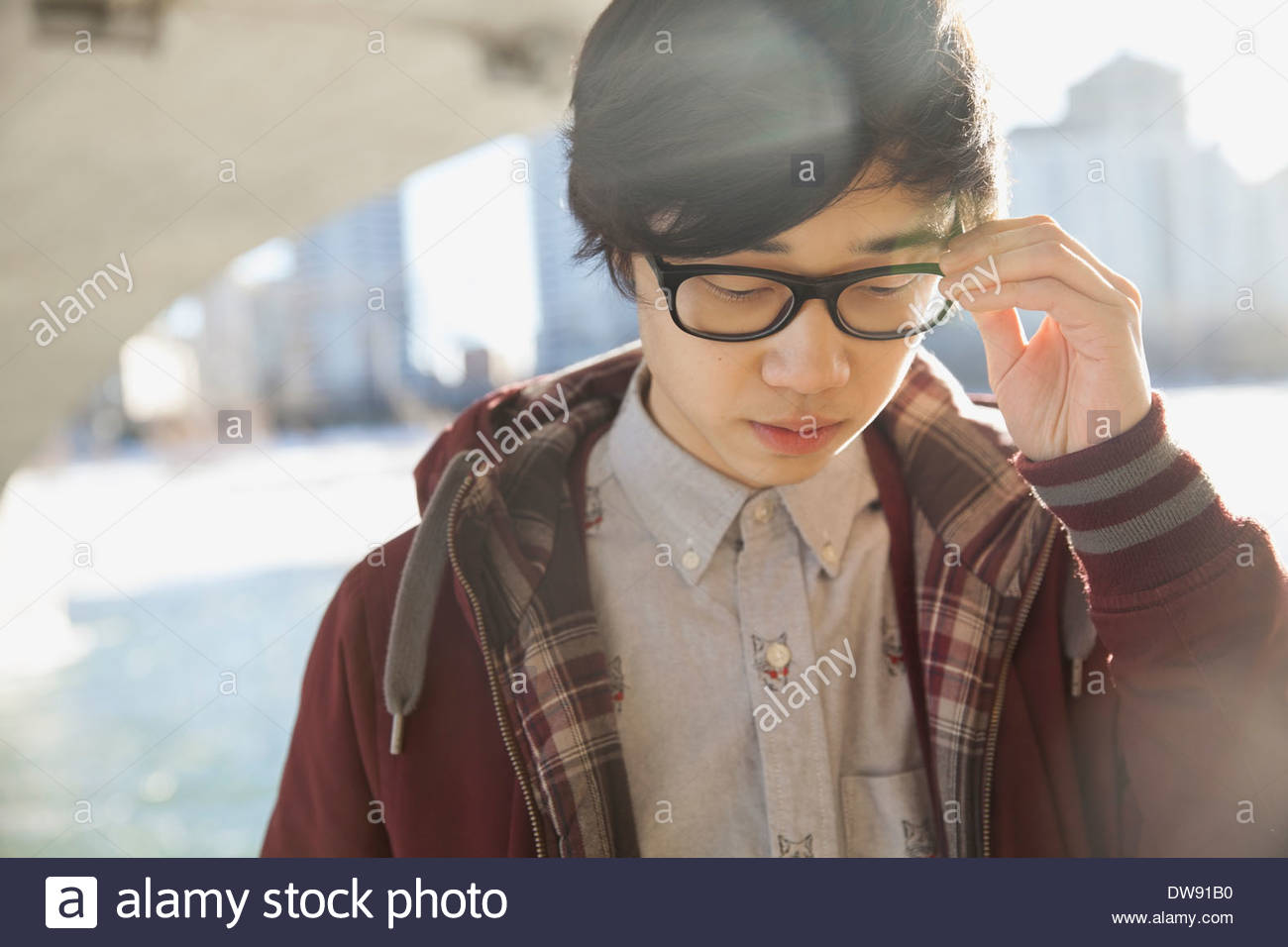 Young man adjusting eyeglasses outdoors Stock Photo