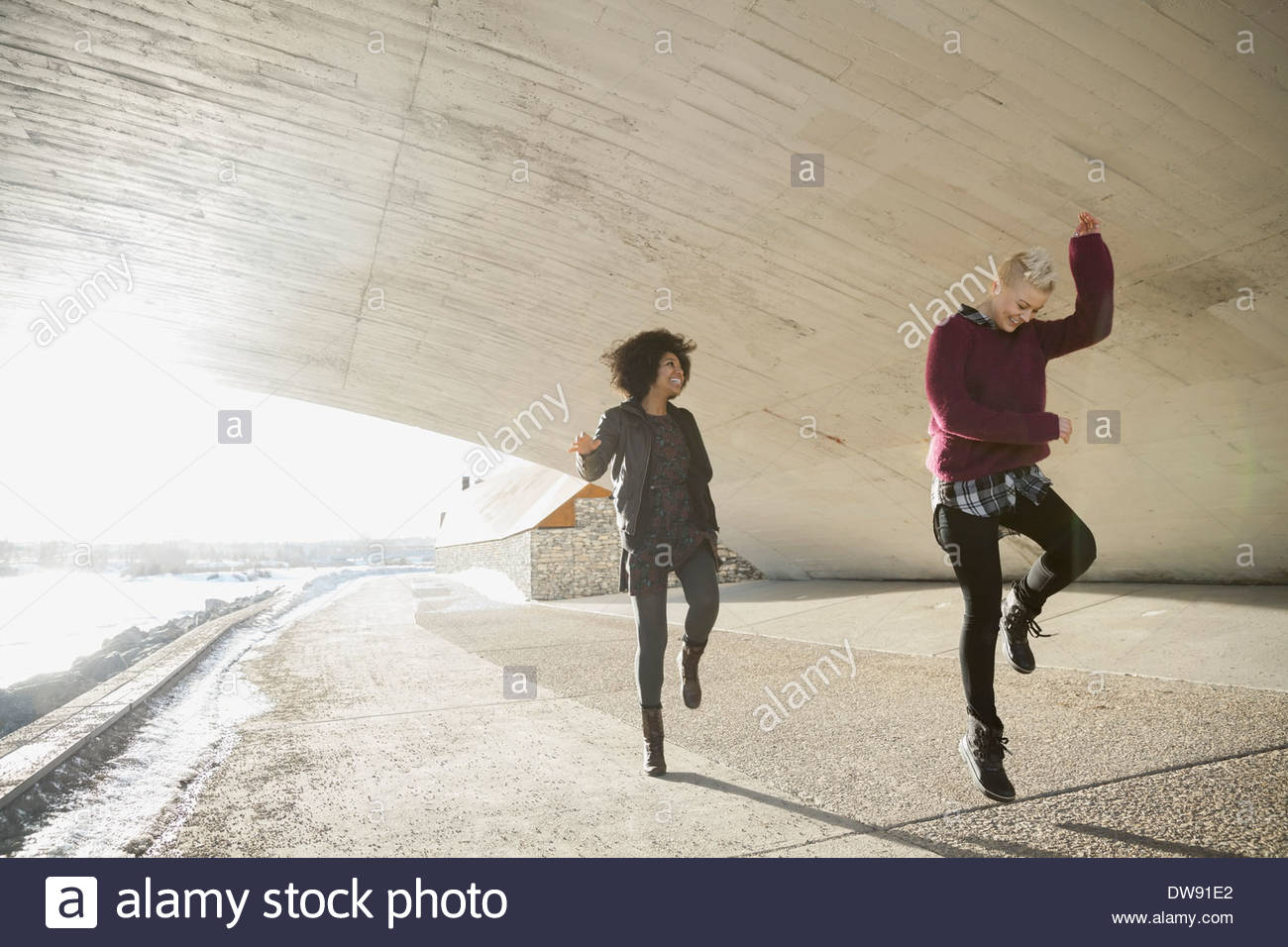 Female friends dancing under city bridge Stock Photo