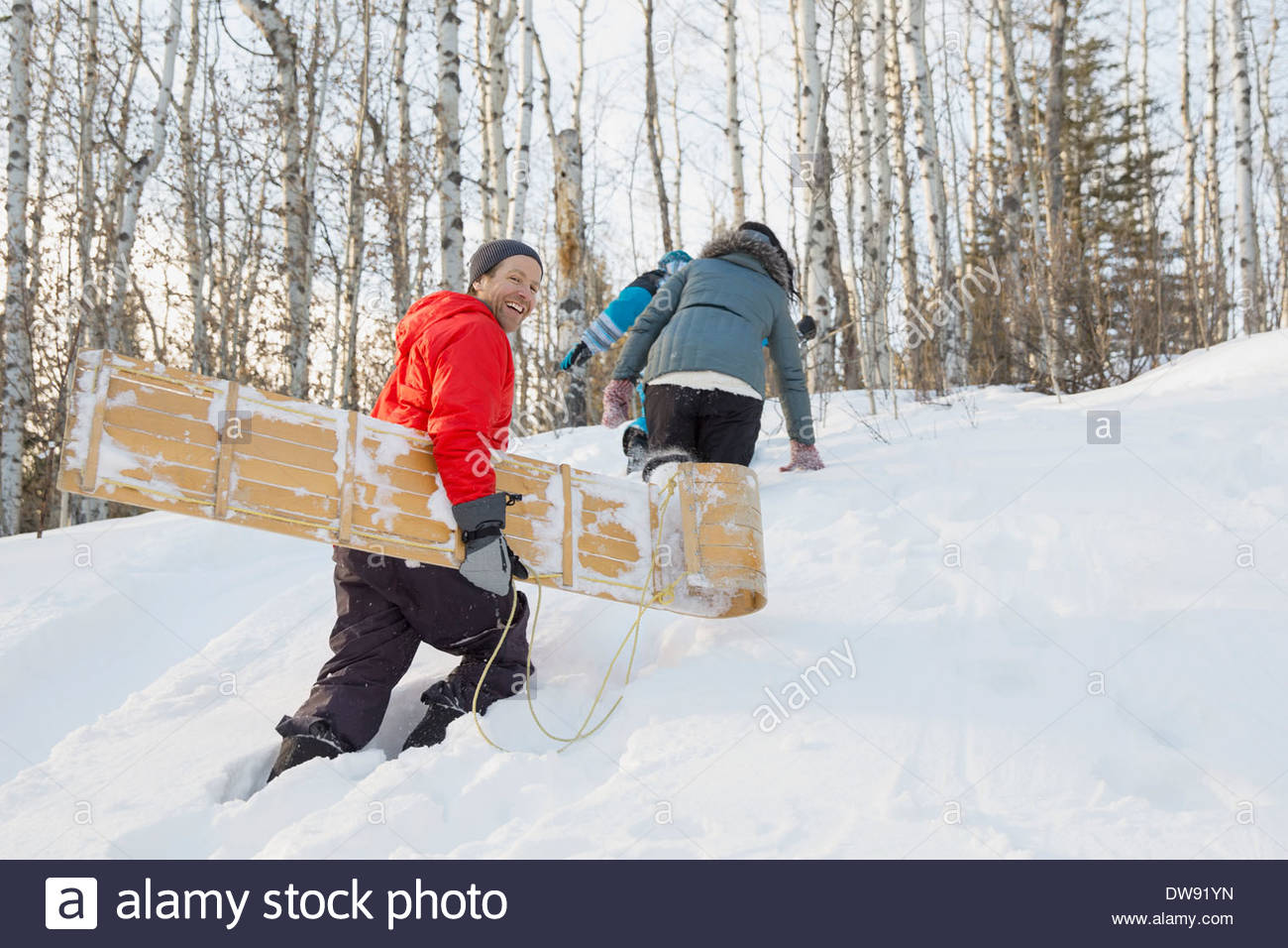 Family walking up hill with toboggan Stock Photo Alamy
