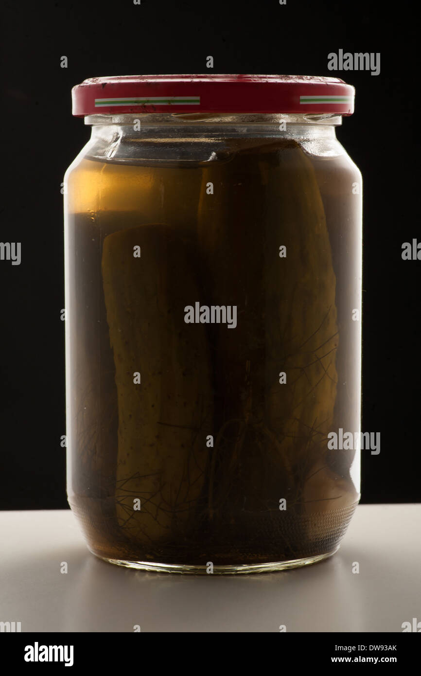 Old Pickle Jar green cucumber's black background on table Stock Photo