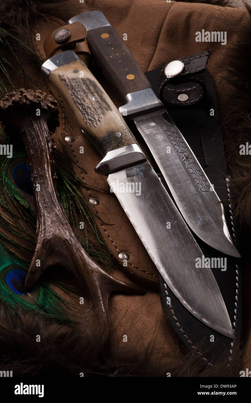 Hunting knives on dark background with antler. Skin sheath and metal