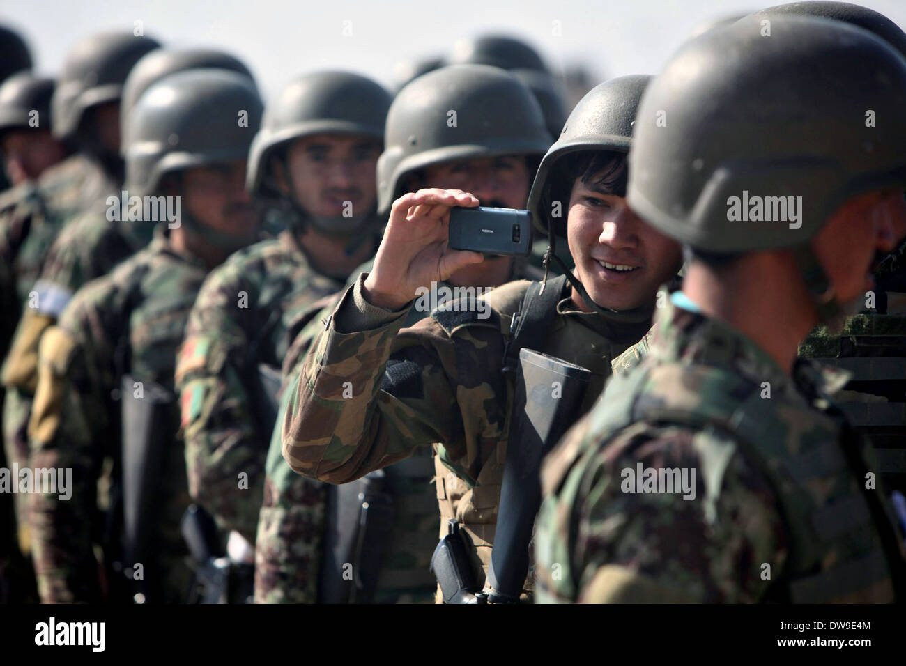 A soldier with the Afghan National Army snaps a photo of an Mi-17 helicopter with his cell phone during a training exercise February 19, 2014 at Camp Shorabak, Helmand province, Afghanistan. Stock Photo