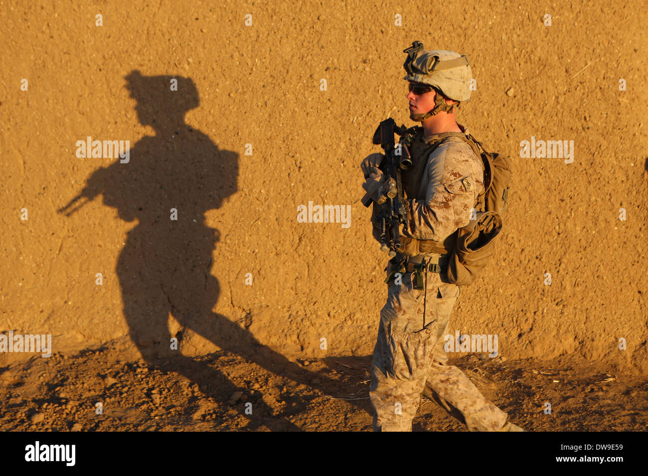 A US Marine patrols outside of Camp Leatherneck during sunset February 14, 2014 in Helmand province, Afghanistan. Stock Photo