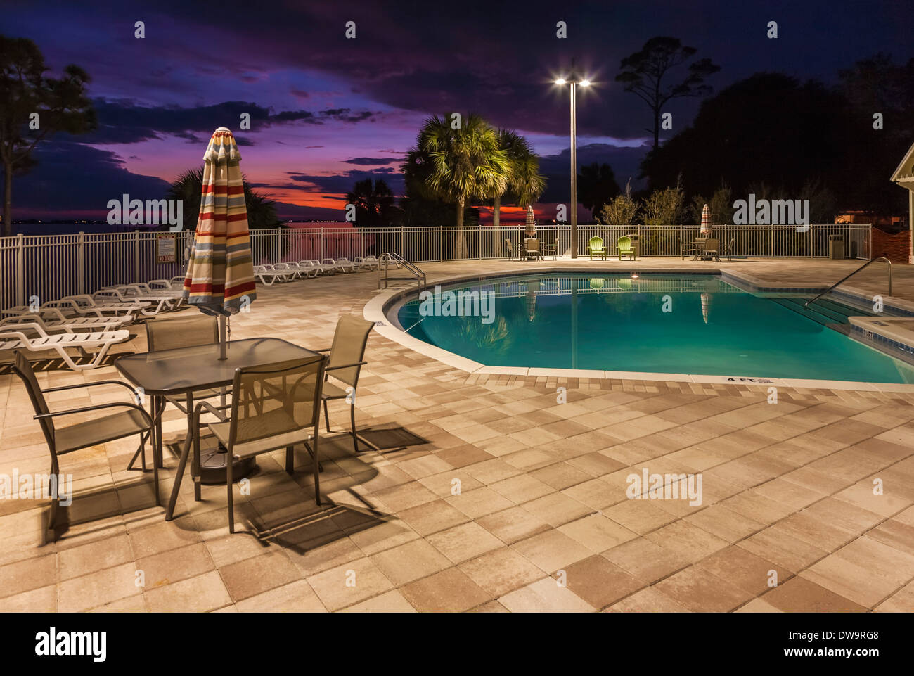 Outdoor swimming pool with concrete tile deck at sunset in Navarre, Florida Stock Photo