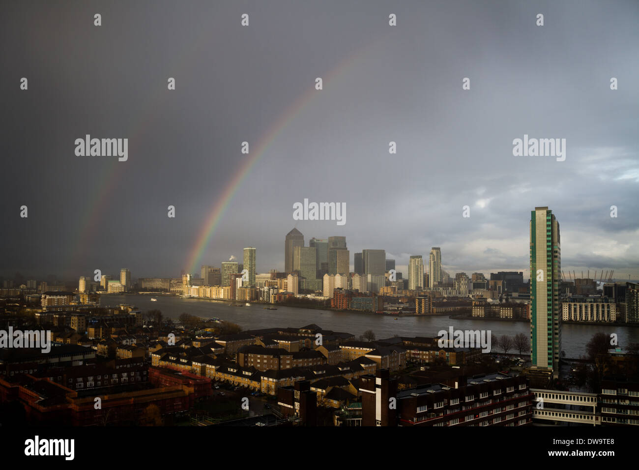 UK Weather: Colourful rainbow breaks during a brief rainstorm over south east London including Canary Wharf business park Stock Photo