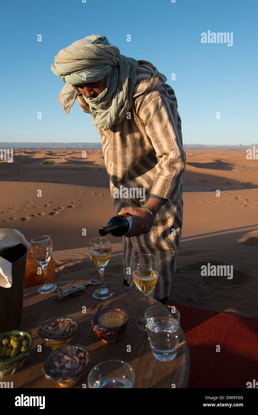 Tuareg man pouring wine in wineglass at Erg Chigaga Luxury Desert Camp in Sahara Desert, Souss-Massa-Draa, Morocco Stock Photo