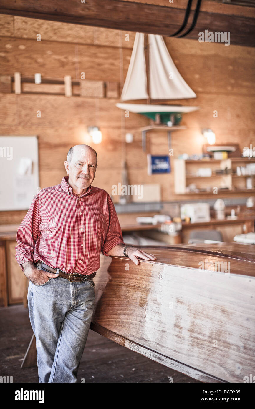 Senior man standing in boat-building workshop Stock Photo