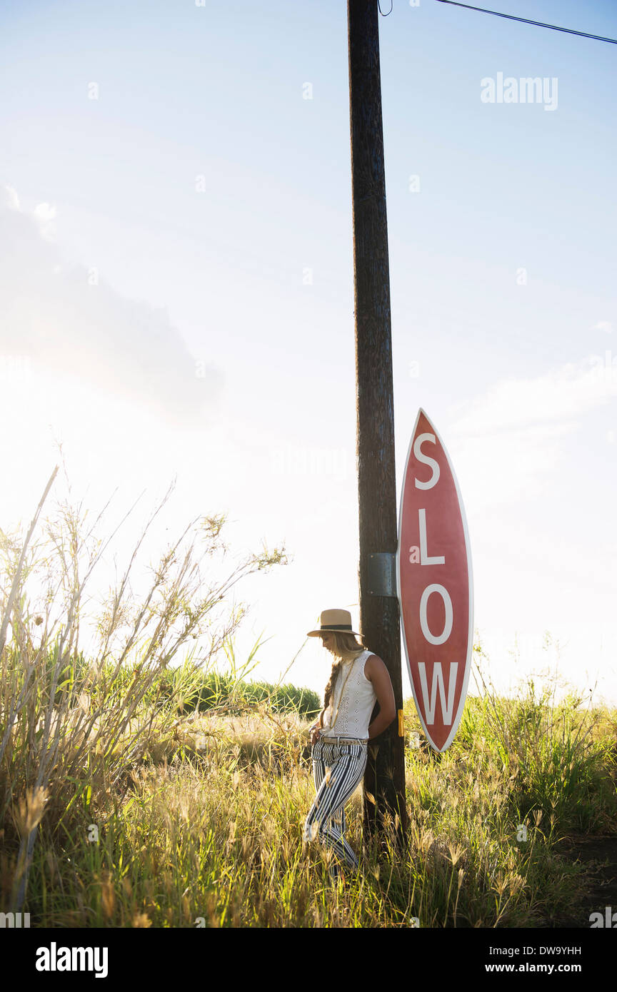 Young woman leaning on sign post Stock Photo