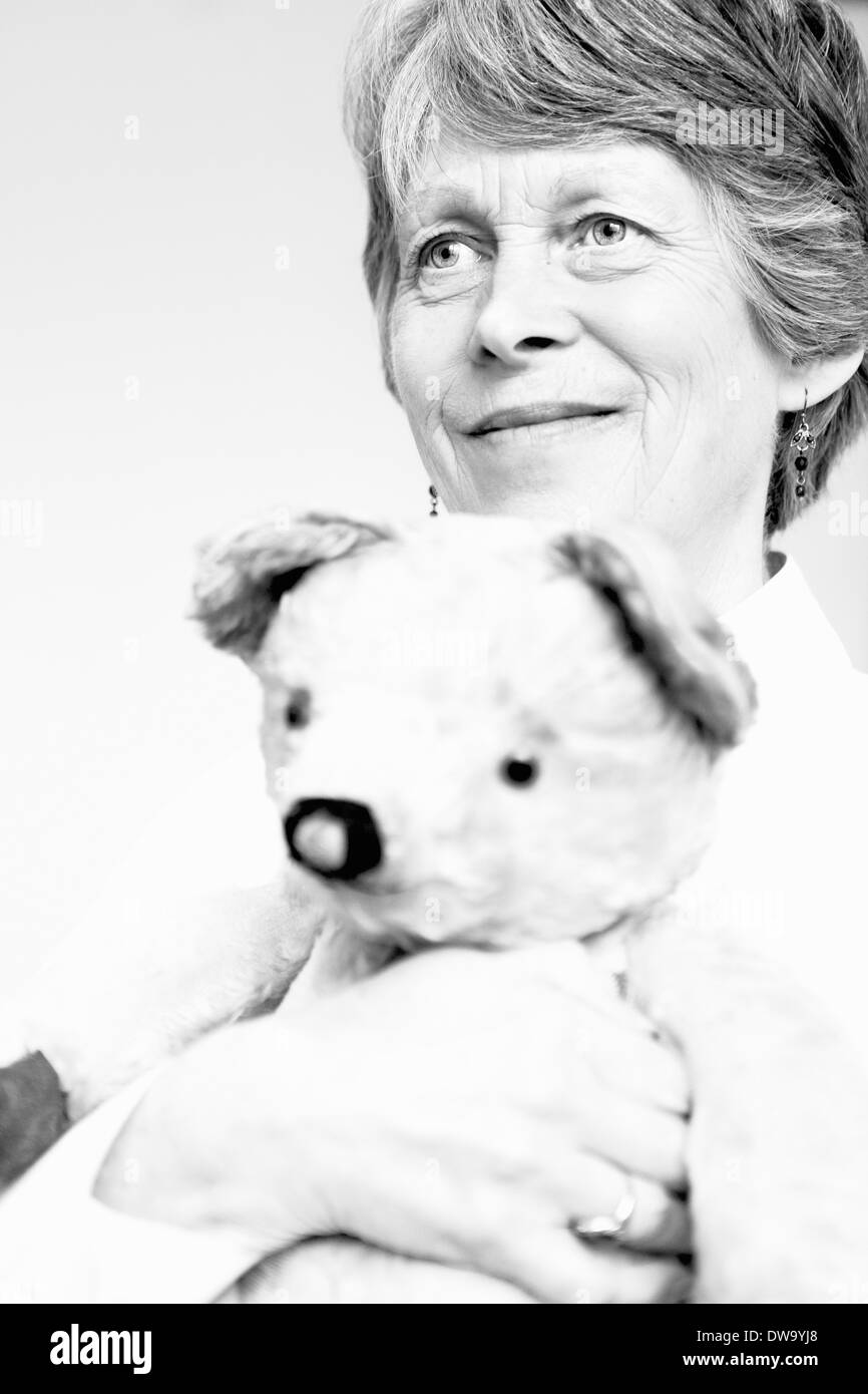 Black and white studio portrait of senior woman holding teddy bear Stock Photo