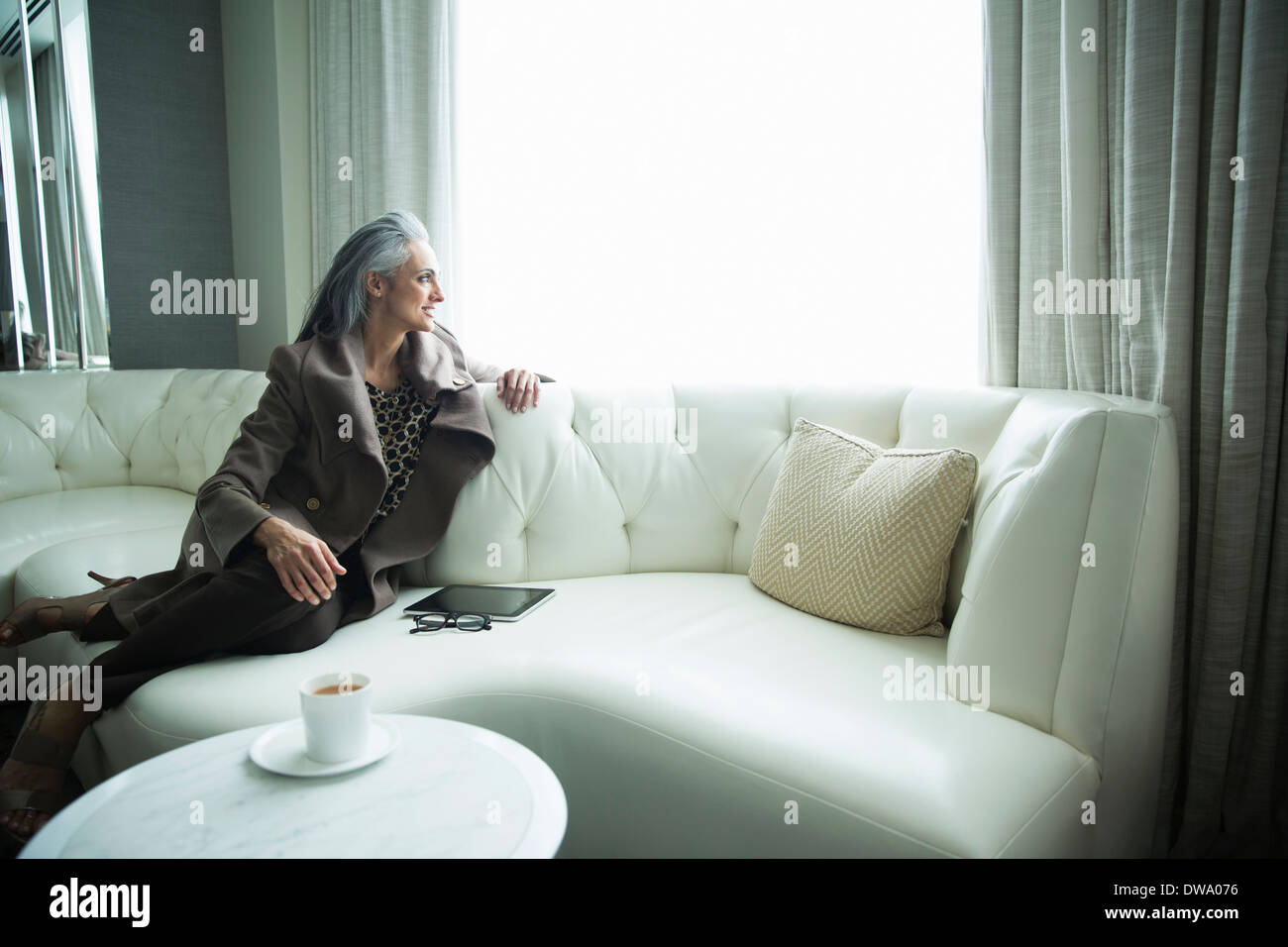 Portrait of mature woman reclining on white luxury sofa Stock Photo Alamy