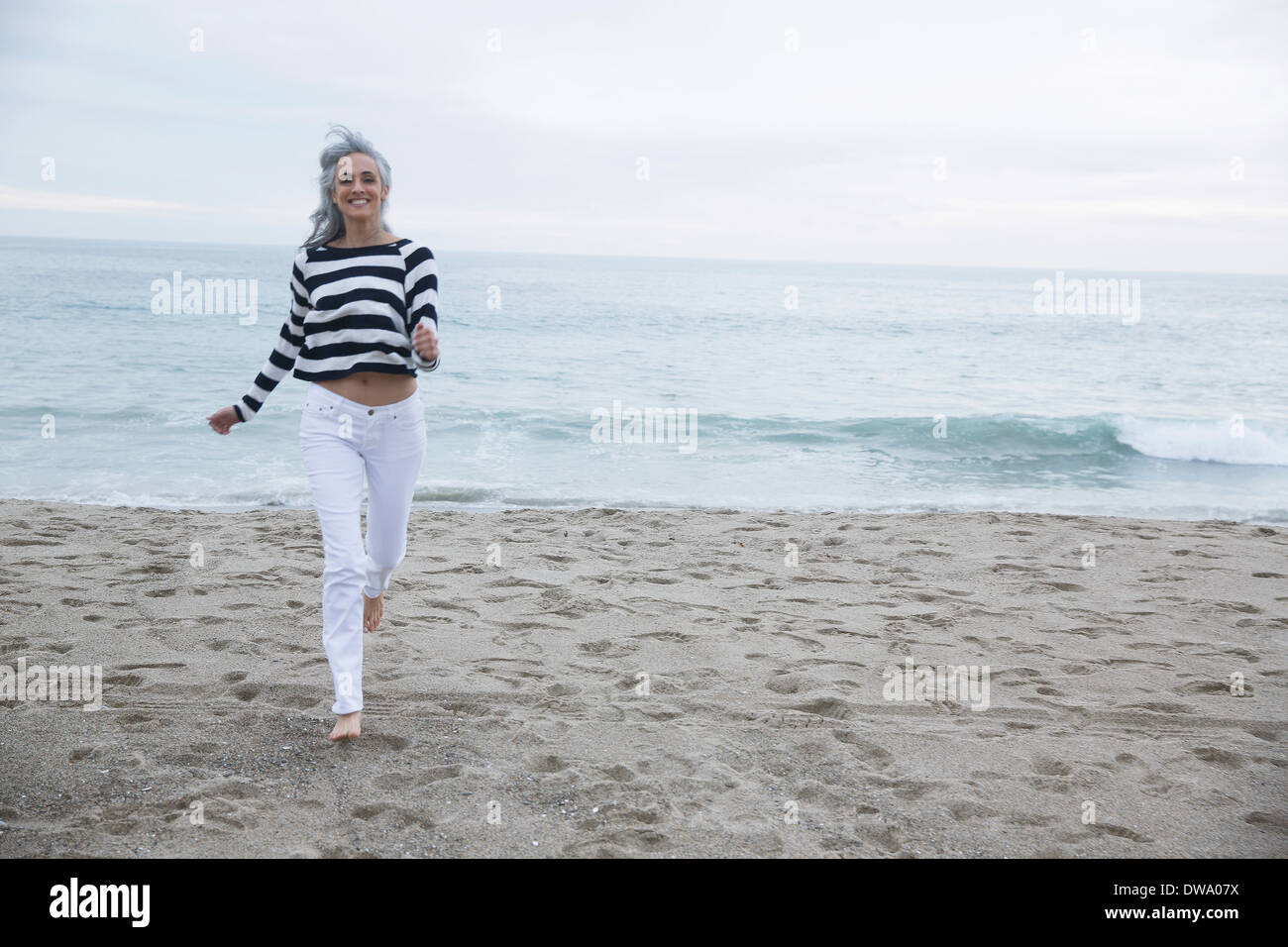 Mature woman running on beach, Los Angeles, California, USA Stock Photo