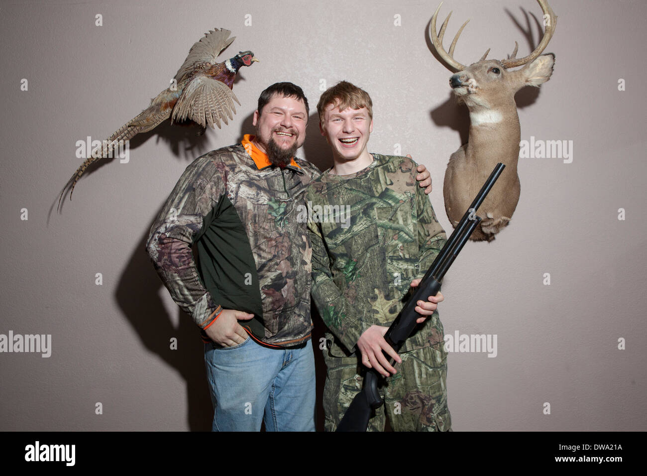Home portrait of father and teenage son holding shotgun Stock Photo