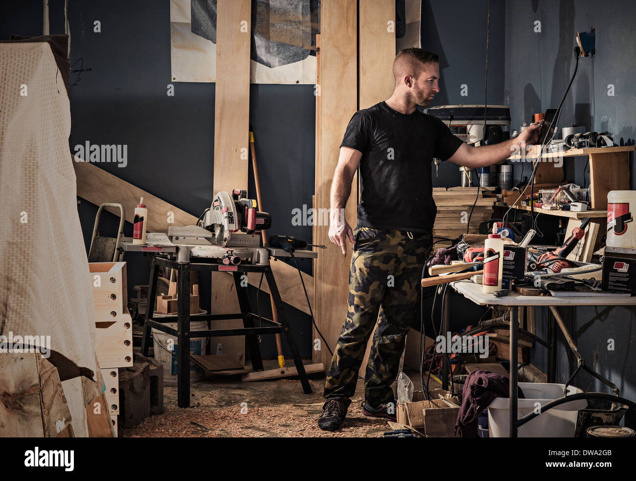 Male carpenter searching shelves in workshop Stock Photo