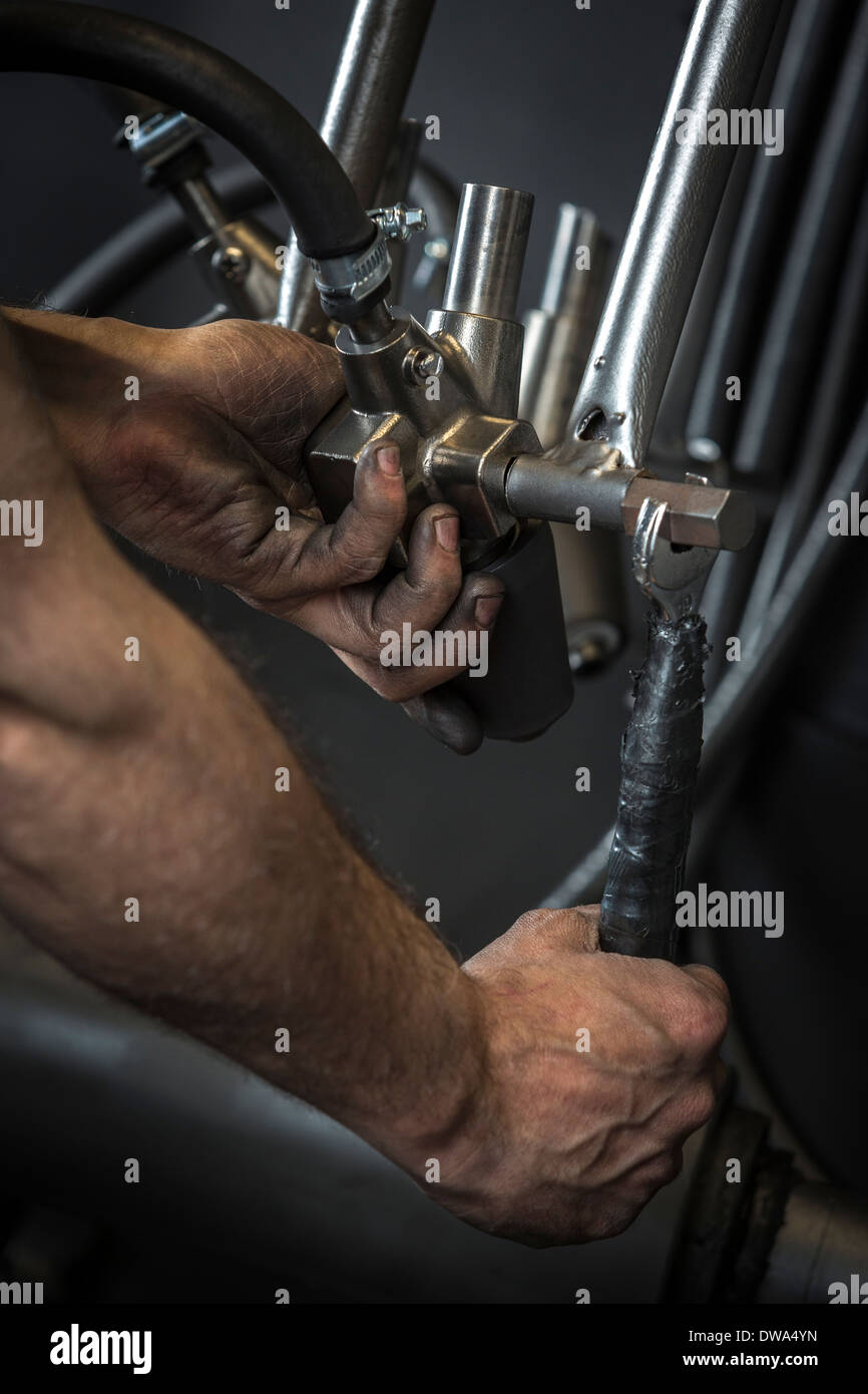 Manual worker's hands. Here an operator is positioning a shot blasting machine nozzle. Positionnement d'une buse de grenailleuse Stock Photo