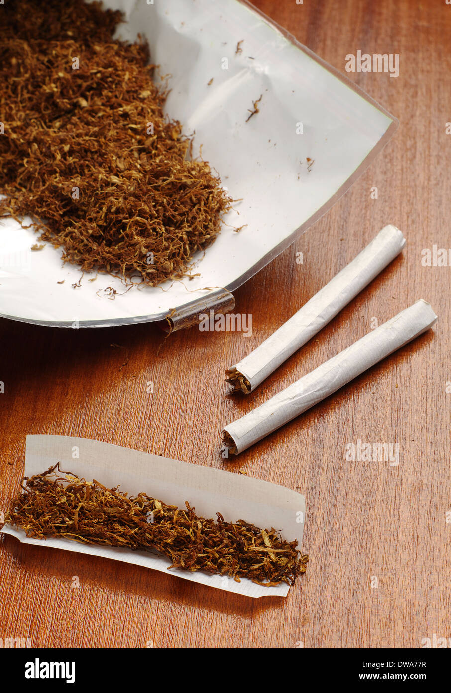 Tobacco and hand rolled cigarettes on brown table Stock Photo