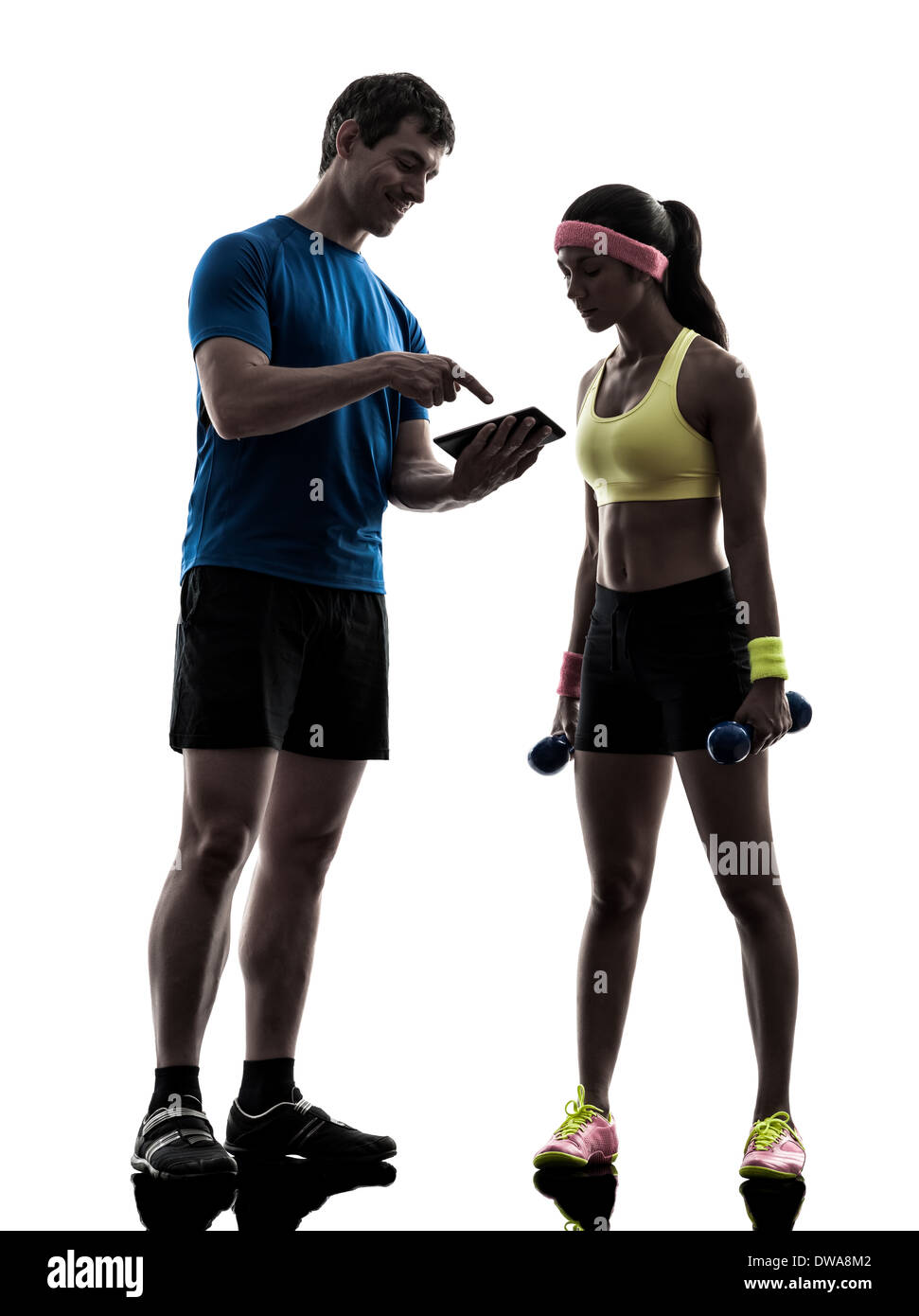 one woman exercising fitness workout with man coach using digital tablet in silhouette on white background Stock Photo