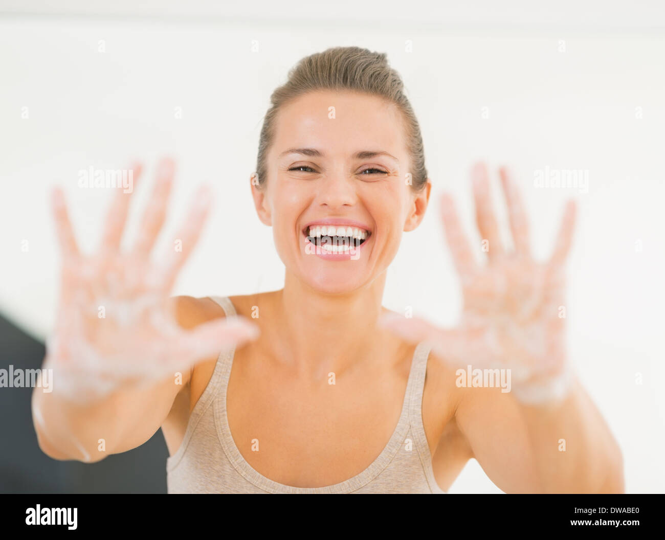 Portrait of smiling young woman showing hands with soap foam Stock Photo