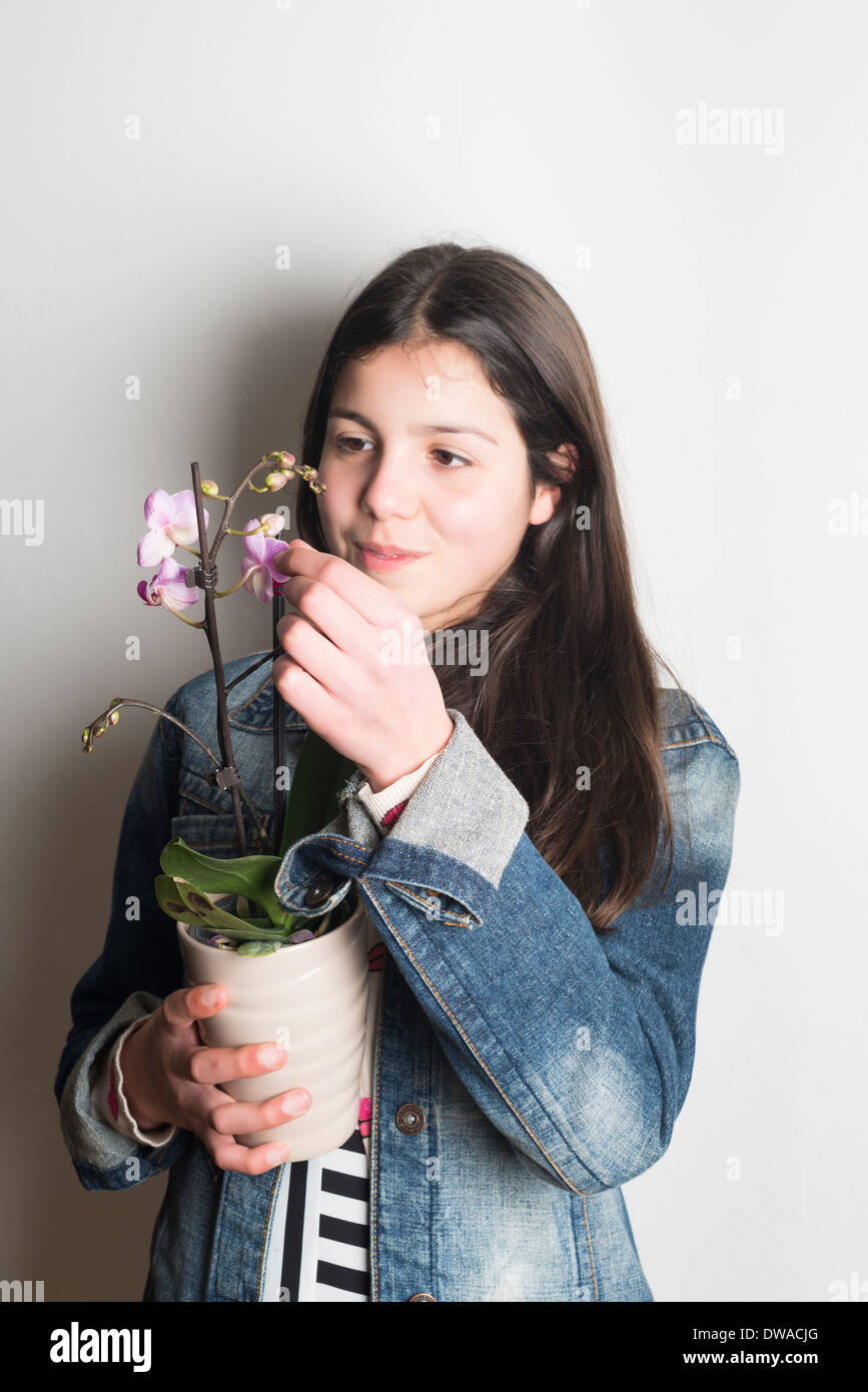 Teenage girl admires orchid plant Stock Photo