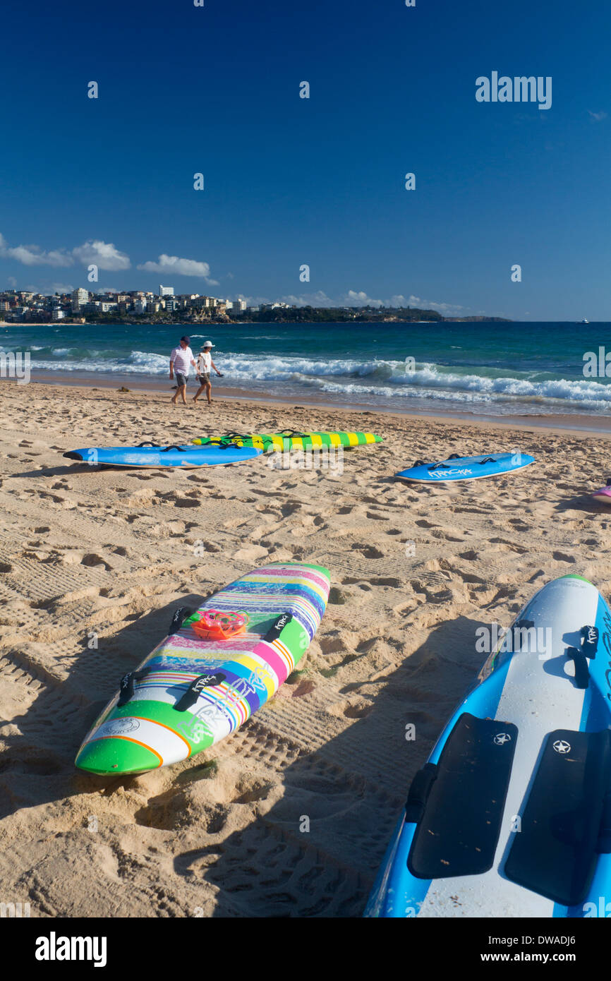 Manly North Steyne Beach with surfboards in foreground and couple walking along shoreline Sydney New South Wales NSW Australia Stock Photo