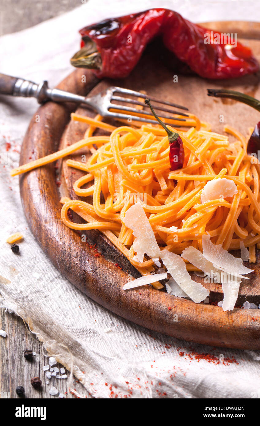 Orange tomato spaghett (tagliolini al pomodoro) with grilled red paprika and cheese parmesan served on wooden cutting board Stock Photo