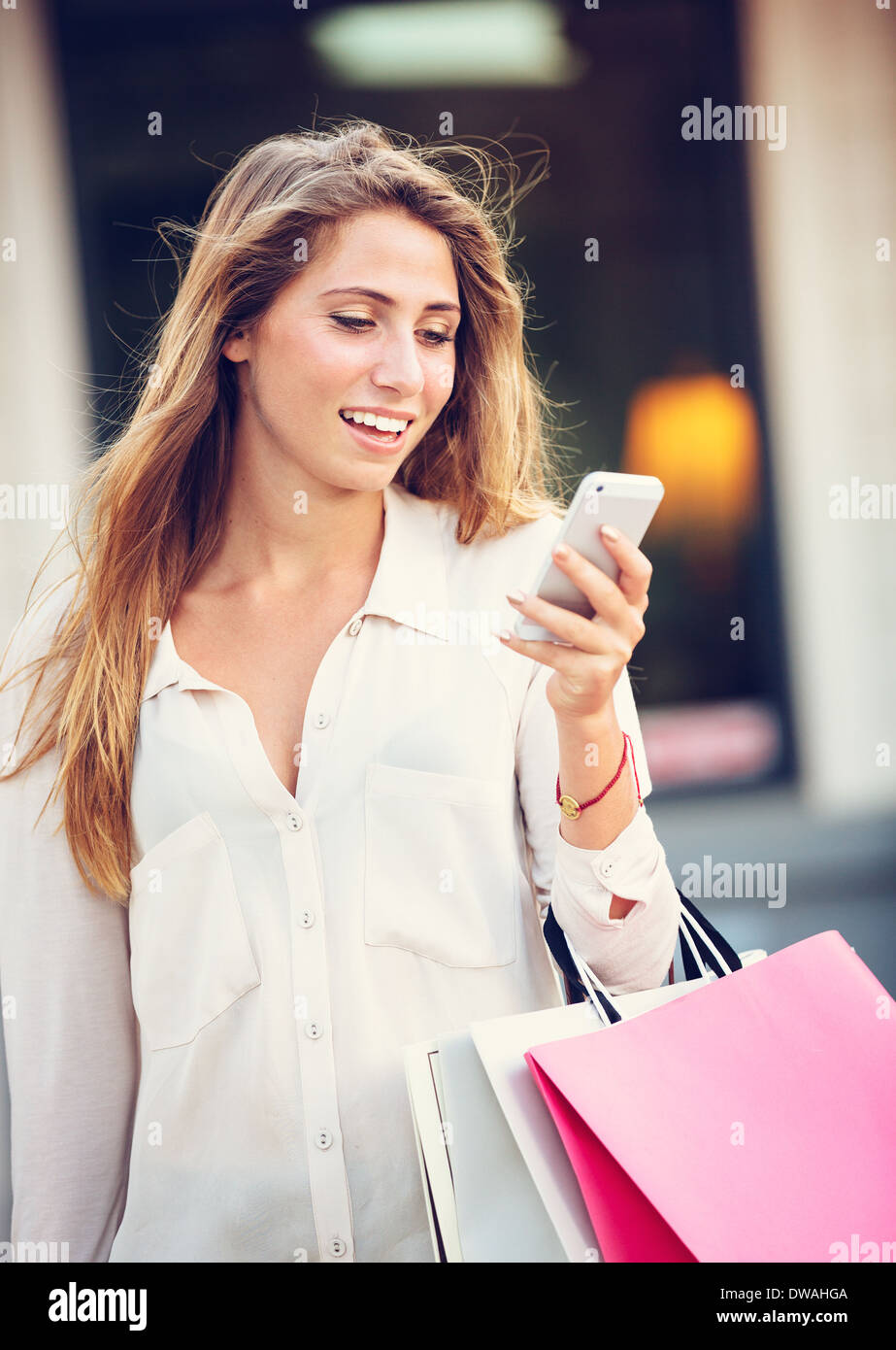 Attractive young woman shopping at the mall using cell phone Stock Photo