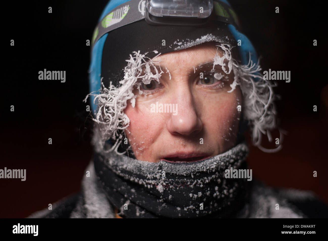 Night time portrait of an outdoors woman with frost on her face, hair and eyelashes Stock Photo