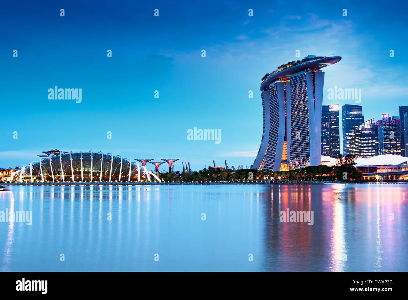 Gardens by the Bay and its conservatories and the Marina Bay Sands Hotel after sunset from the Bay East Garden Stock Photo